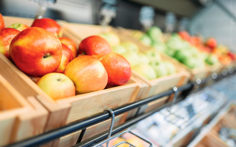 Box with fresh red apples on stand in food store, nobody. Fruit assortment in market