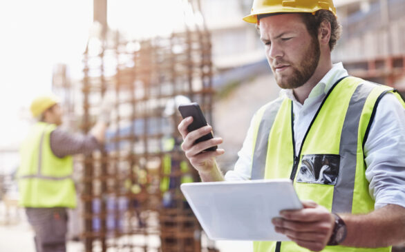 Construction worker digital tablet texting cell phone at construction site