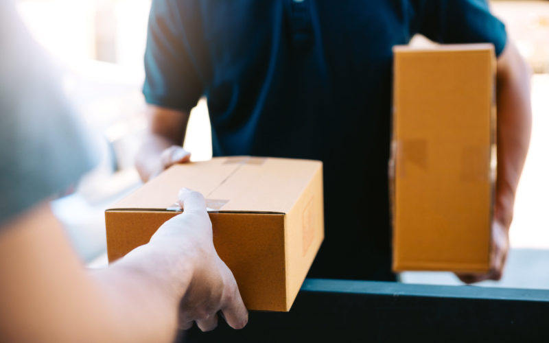 Close up of hands cargo staff are delivering cardboard boxes with parcels inside to the recipient's hand.