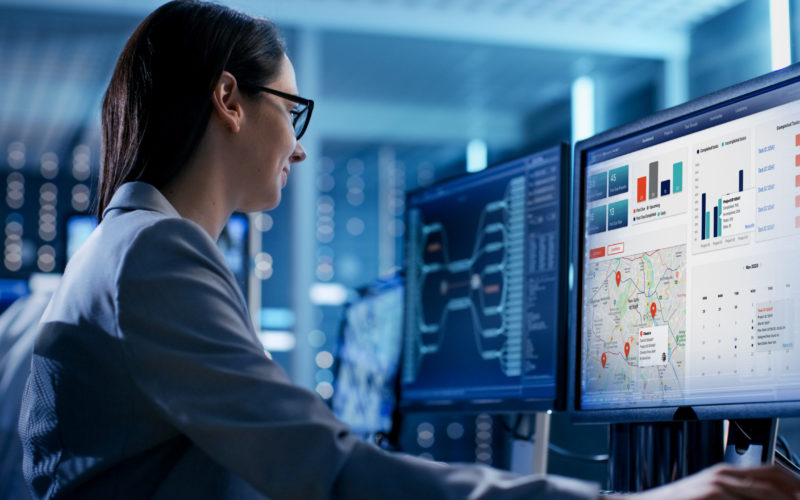 Close-up Shot of Female IT Engineer Working in Monitoring Room. She Works with Multiple Displays.