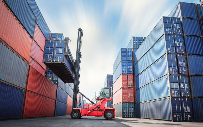 Container Ship Loading of Import/Export Freight Transportation Industry, Transport Crane Forklift is Lifting Box Containers at Port Cargo Shipping Dock Yard. Logistic Freighting Ship Service